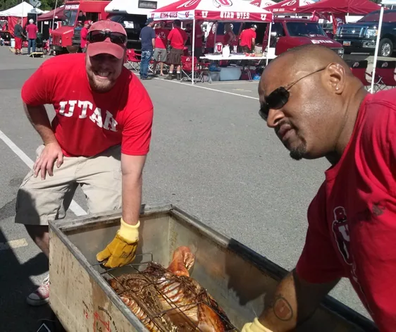 Two crew members tending a pig on the grill, from the Pig Bus archive