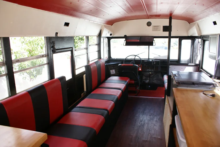 The finished interior: striped benches down one side, a wood counter and flat-top grill on the other