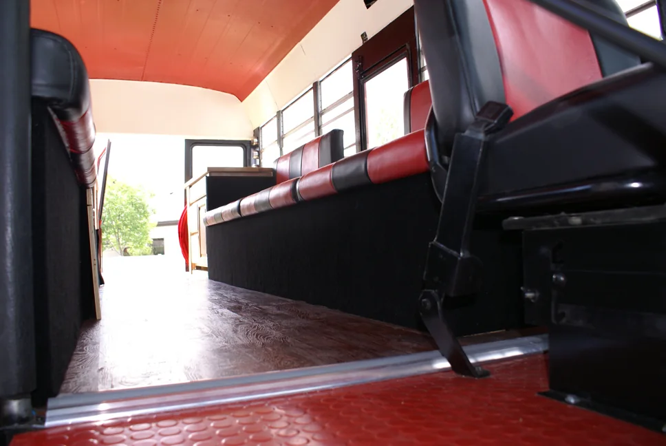 Low view down the aisle: wood floor, red ceiling and the striped benches