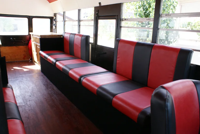 Striped benches along the windows with the wood cabinet at the back of the bus