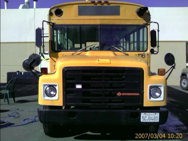 The original yellow Bluebird school bus parked in a lot before the conversion