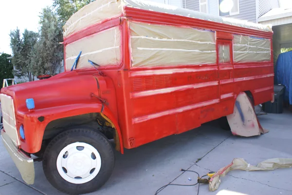 The bus freshly sprayed red with windows and grille still masked