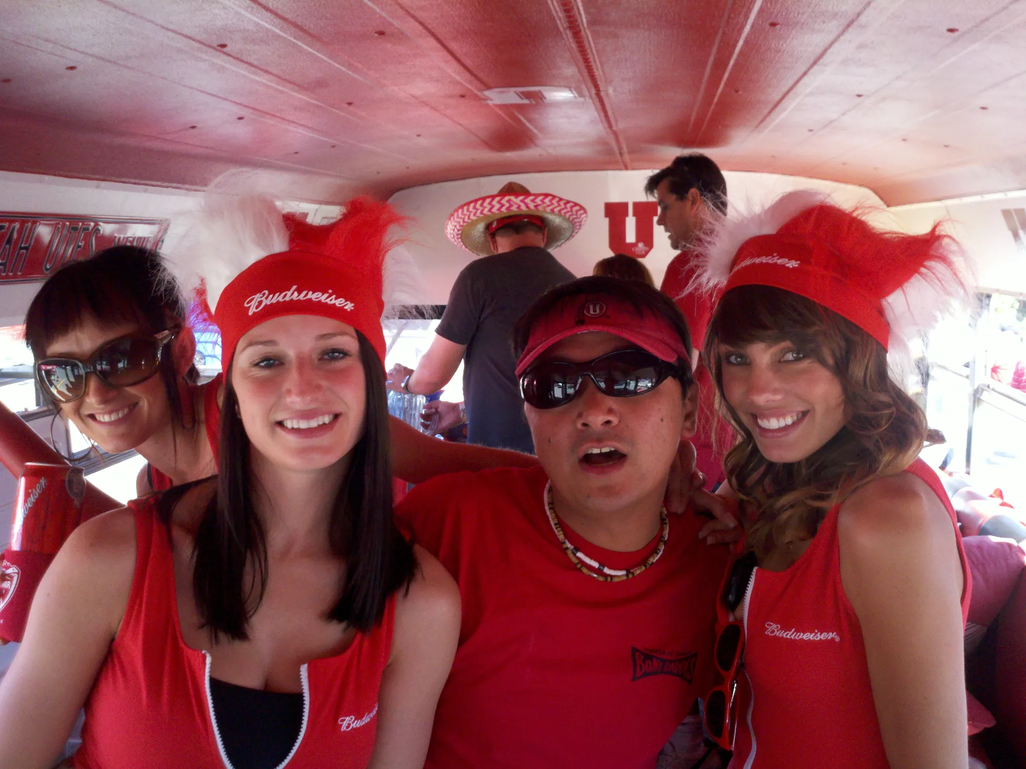 Friends in red feathered hats and sunglasses inside the bus
