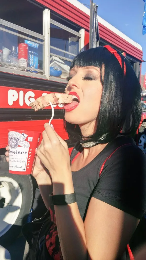 A guest sampling pork beside the red Pig Bus