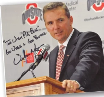 Signed photo of Coach Urban Meyer at a podium, inscribed "The Utah Pig Bus — Go Utes & Go Bucks"