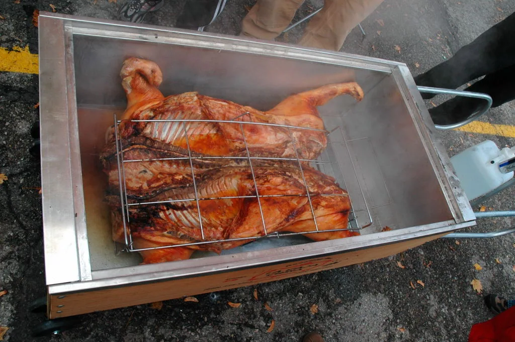 A whole pig roasting inside an open metal roasting box