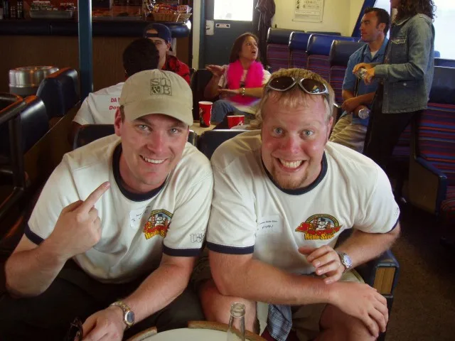 Two friends in team shirts grinning at a restaurant table