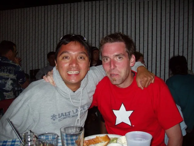 Two friends hugging at a restaurant, one in a red star shirt