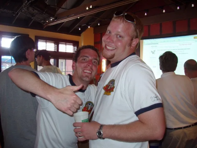 Two friends in matching team shirts giving a thumbs up at a restaurant