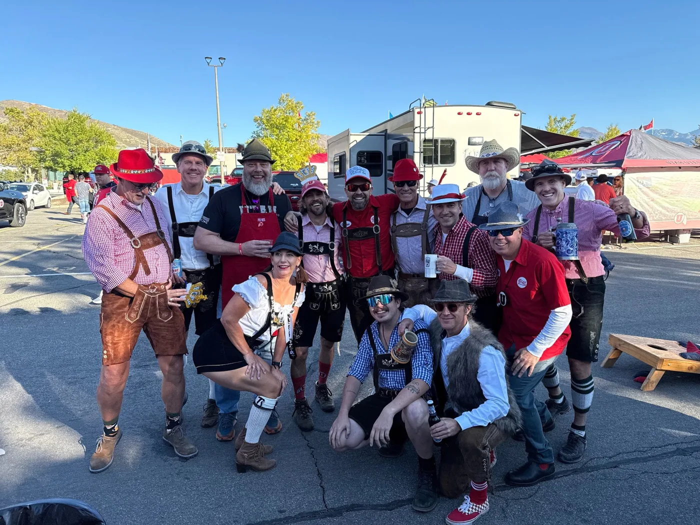 A big group of crew and friends in lederhosen and feathered hats in the lot