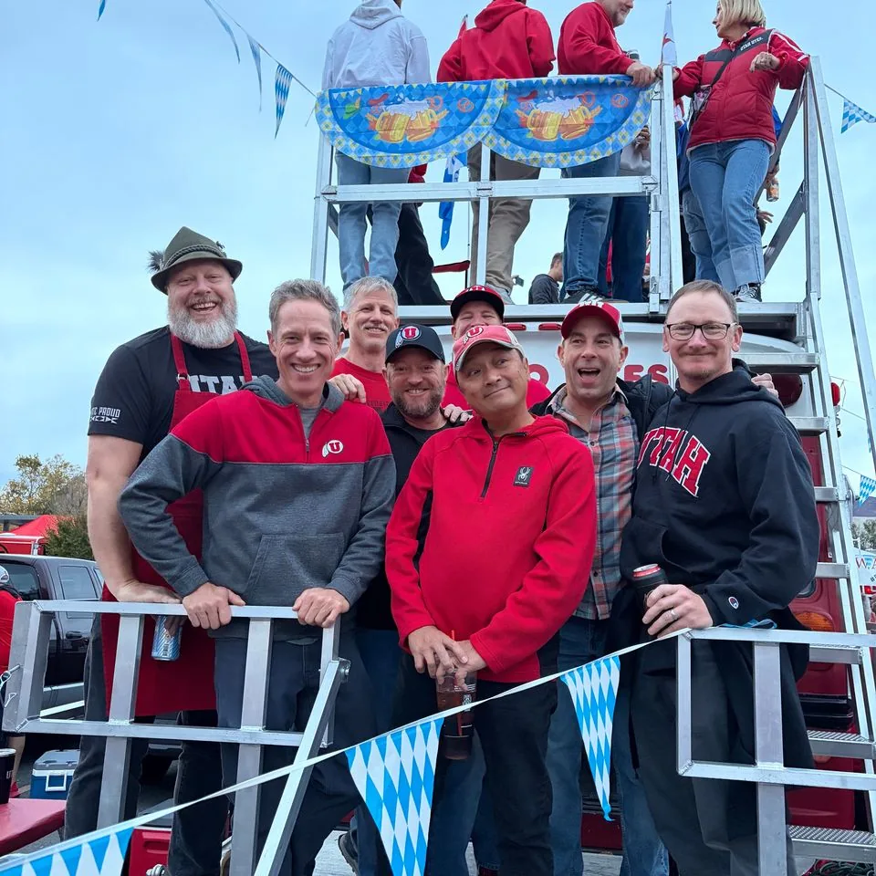 The crew grinning on Porky’s stairs and roof deck under Oktoberfest bunting