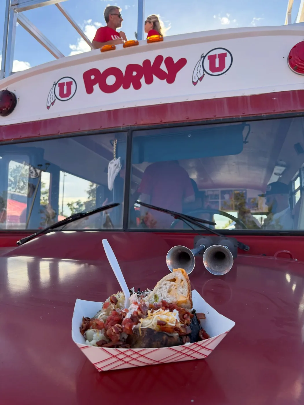 A loaded baked potato with bacon and cheese on Porky’s hood