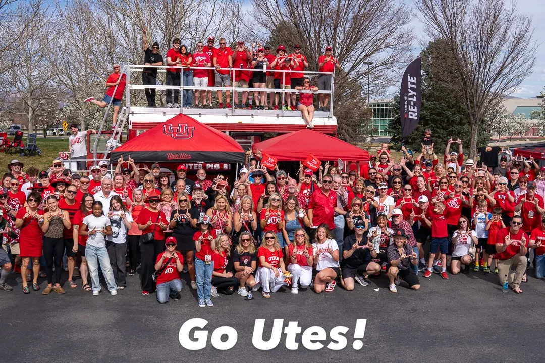 A huge crowd in Utah red posing in front of Porky and on the roof deck, captioned Go Utes!