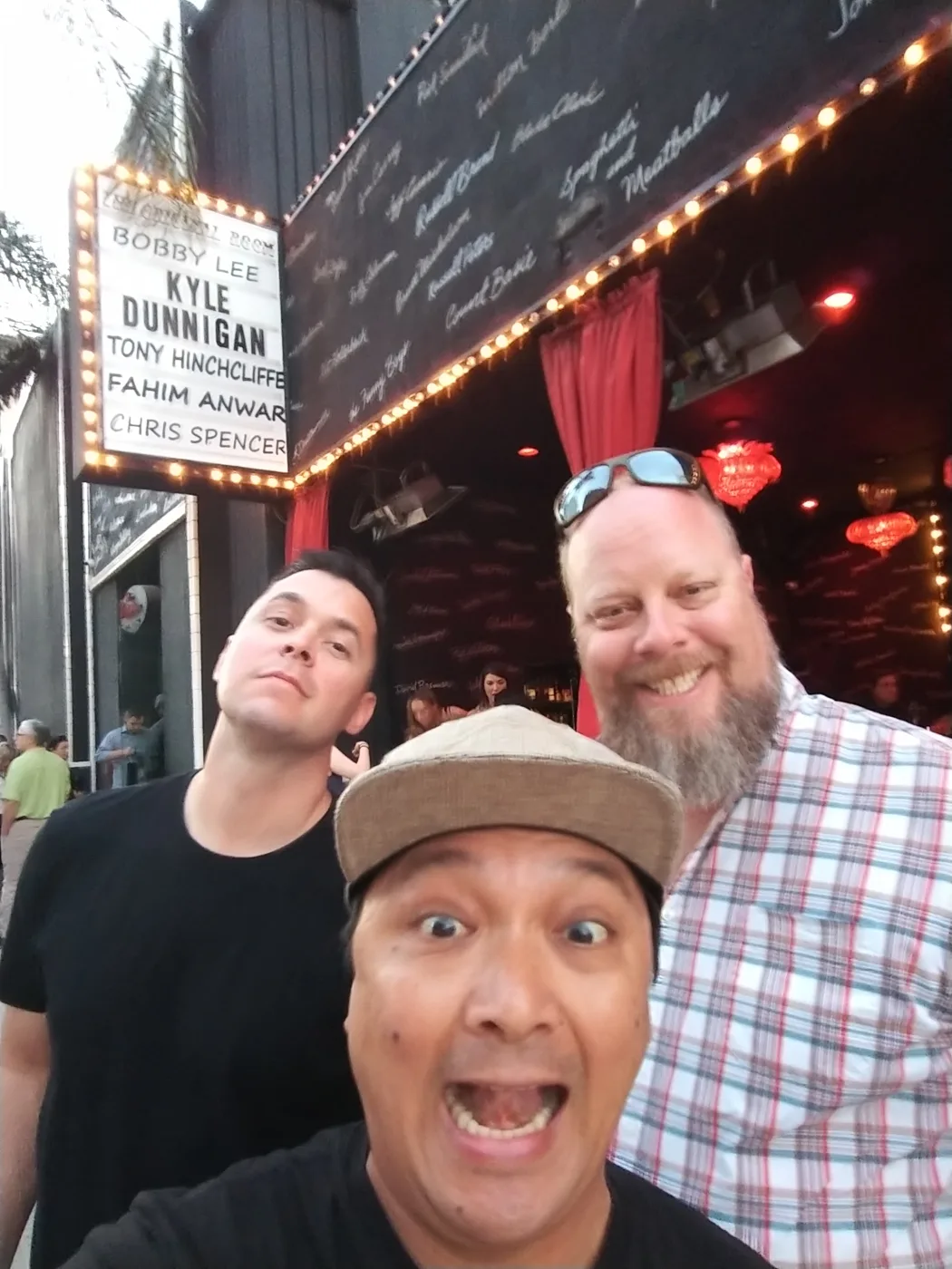 Three friends in a selfie outside a comedy club marquee