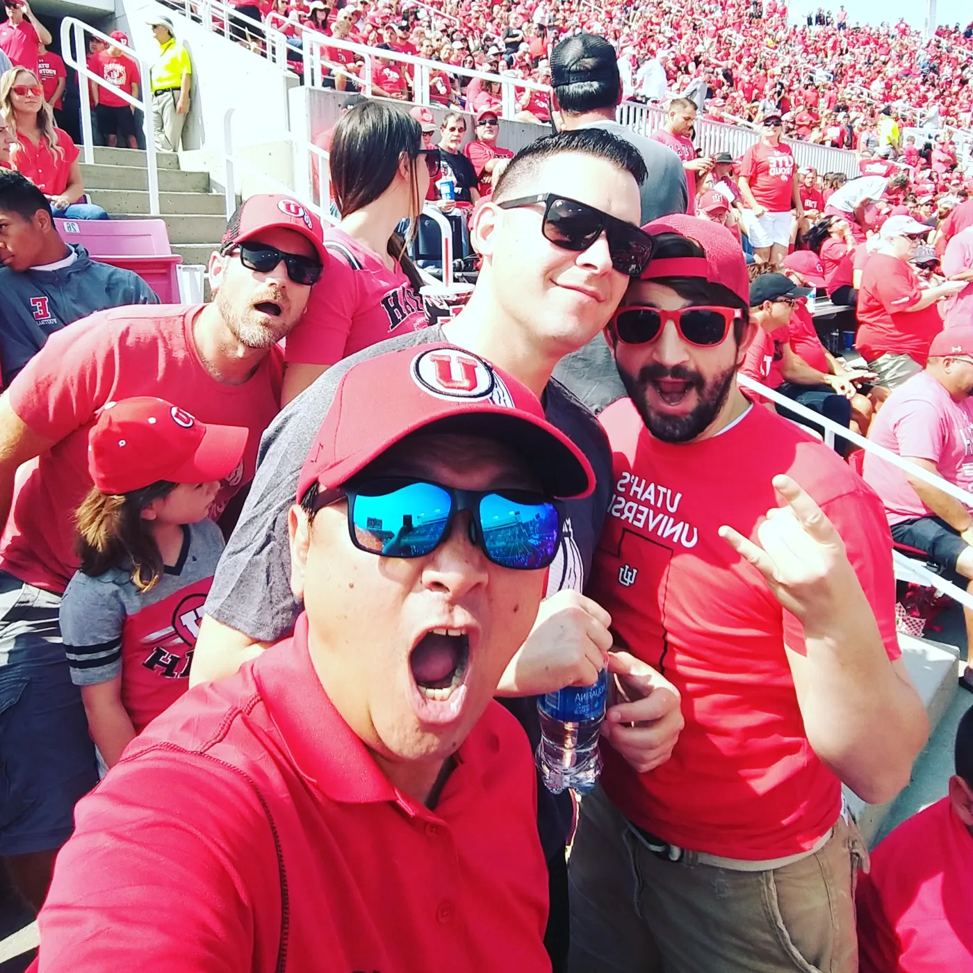 Crew members shouting in a stadium selfie among a sea of red fans